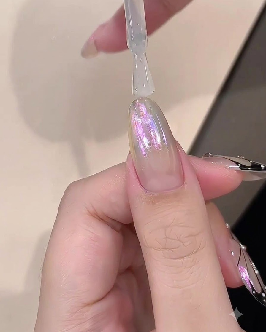 A brush applying a clear layer of builder gel over a chrome-finished nail.