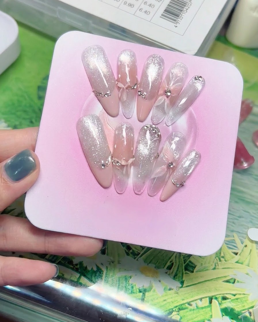 Macro shot of layered sheer gauze butterfly and bow charms mounted on translucent gradient nail tips.