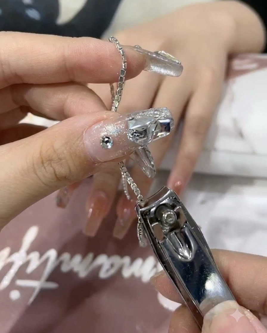A close-up of nail clippers cutting a small segment of shiny silver chain.