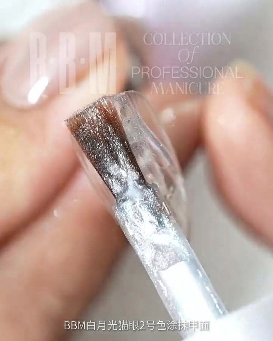 A nail brush applying silver glitter cat-eye gel onto a clear nail surface.