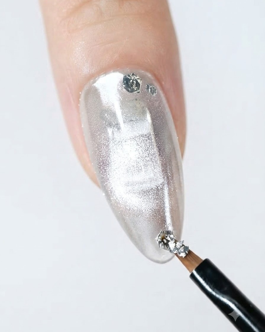 A fine liner brush applying silver glitter flakes onto the edge of a finished nail.
