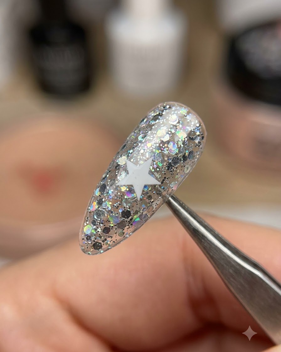 A pair of tweezers lifting a white star sticker off a shimmering glitter nail.