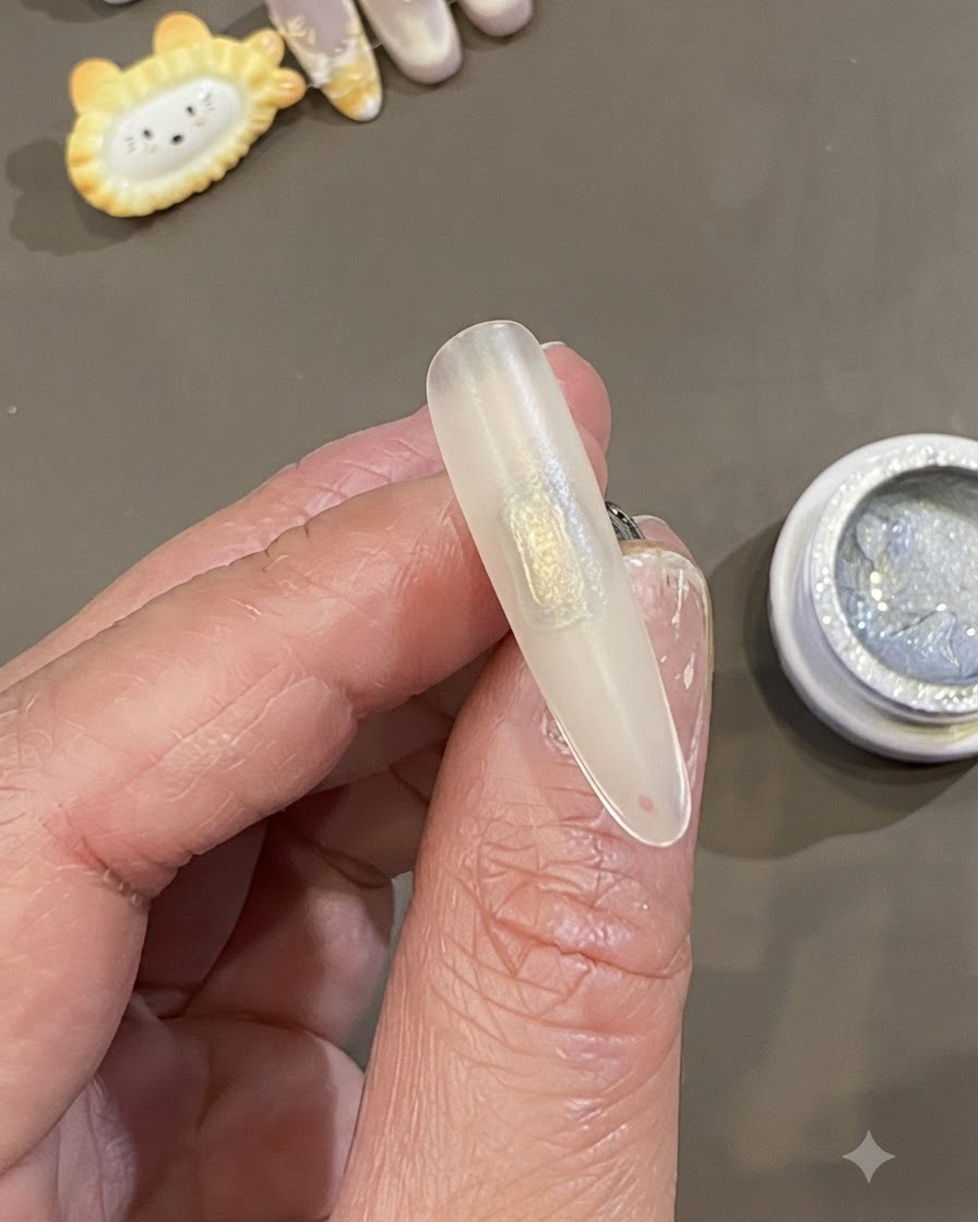 A close-up of a hand holding a prepped, frosted nail tip with a rectangular patch of clear slip gel applied in the center.
