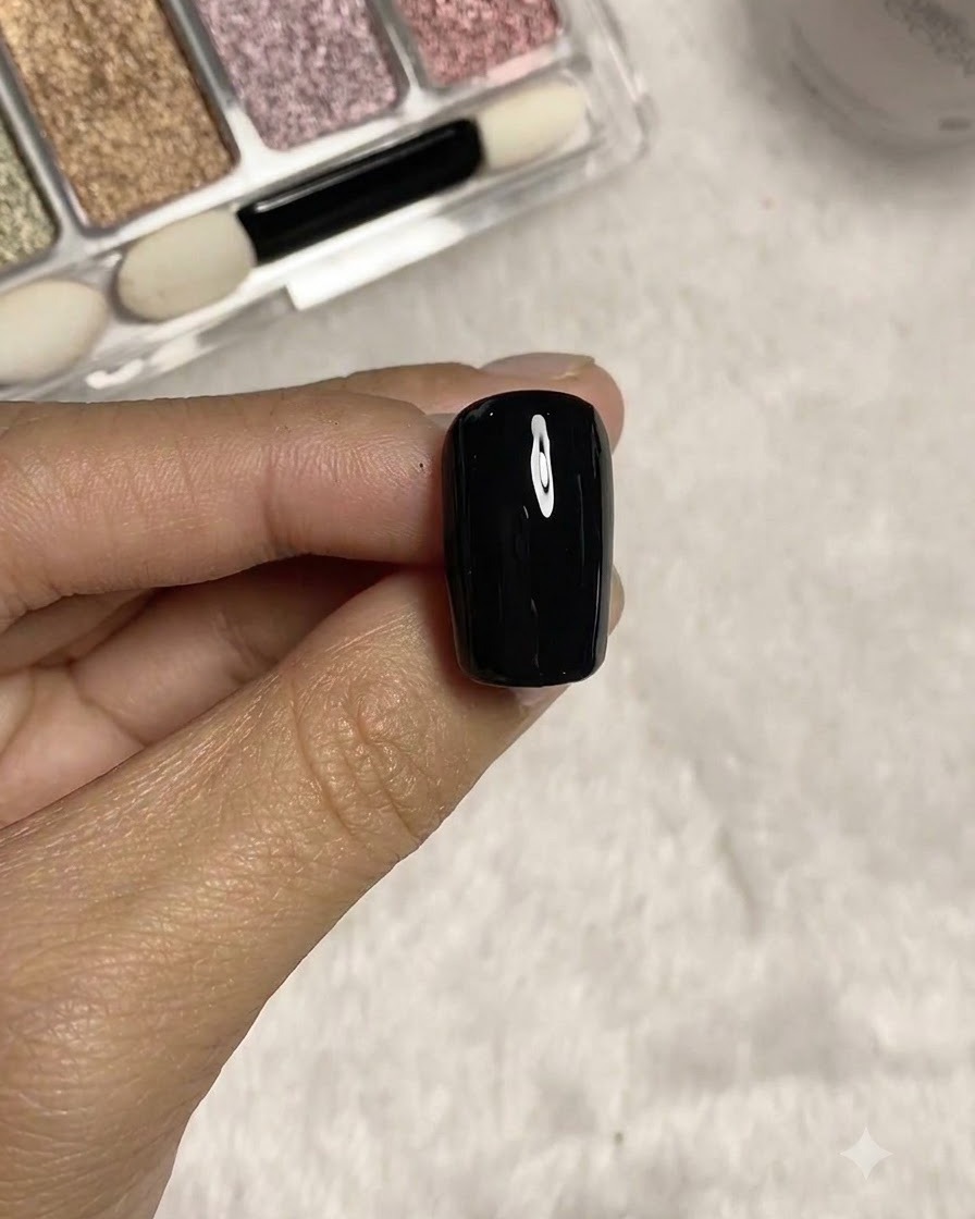 A long liner brush drawing fine dimensional lines on the black textured nail surface.