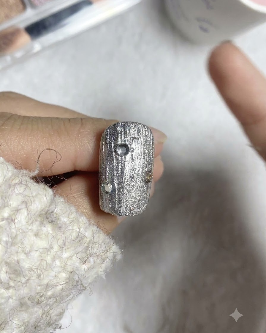 A liner brush placing small steel beads around rhinestones on a textured nail.