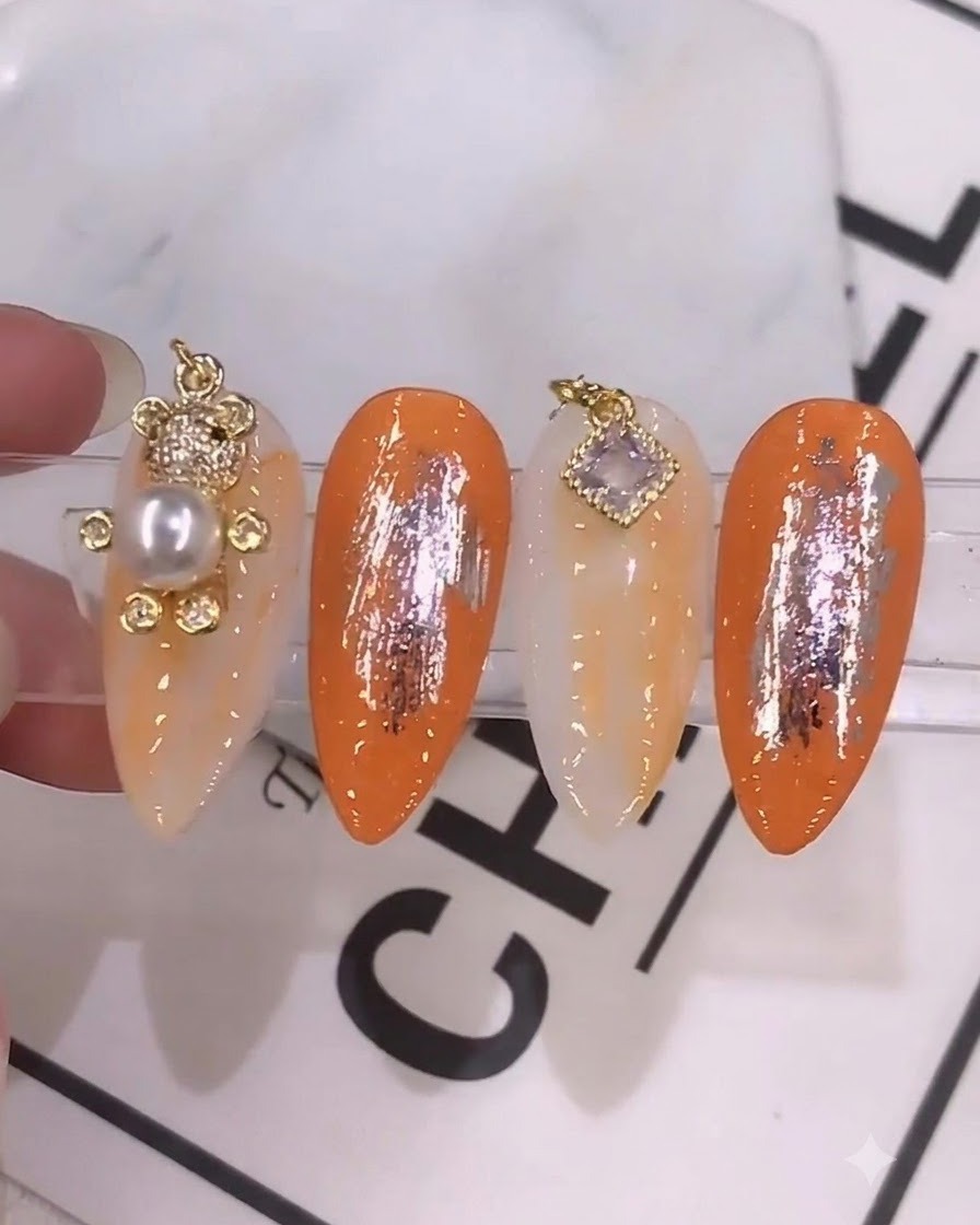 A detailed close-up of a nail brush applying a vibrant orange-toned mixed gel color onto a prepped nail.