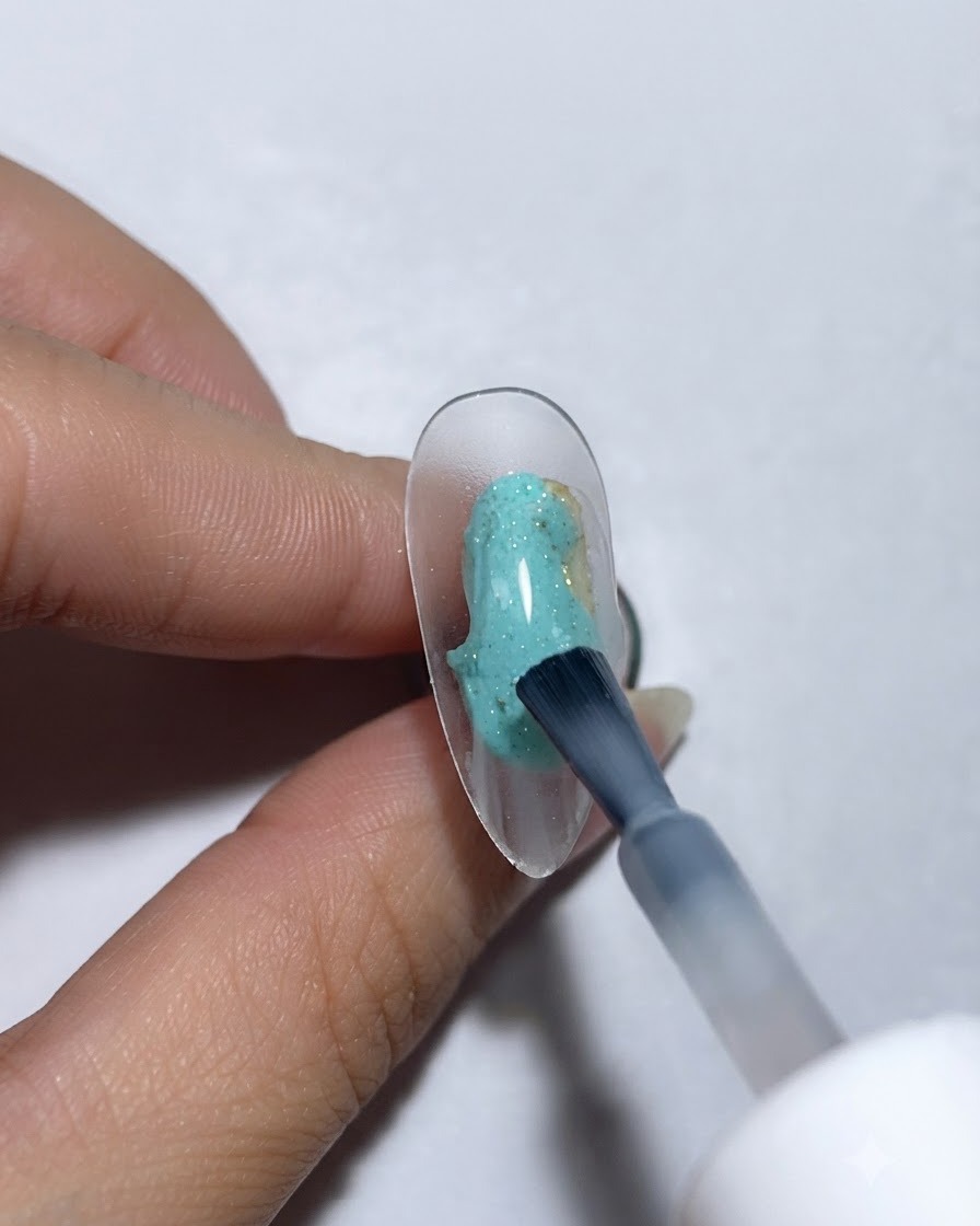 A brush applying protein gel base onto a clear display nail.