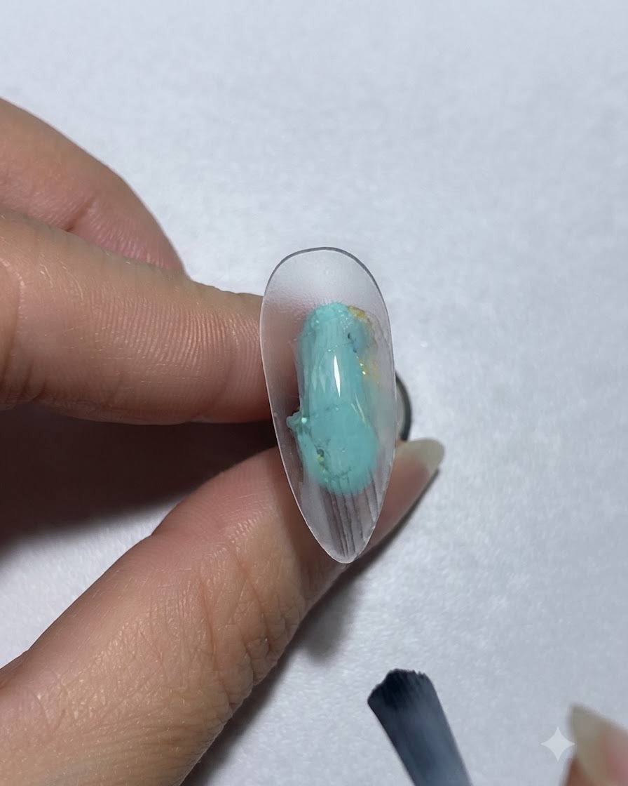 A brush applying greenish-blue paint gel onto a nail.