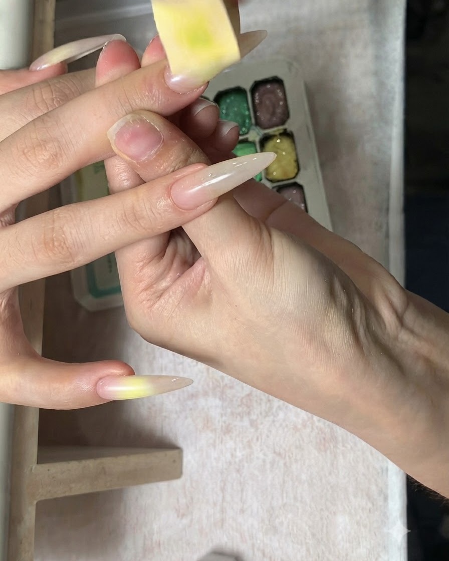 A close-up of a sponge gently dabbing color onto the gradient nail surface.