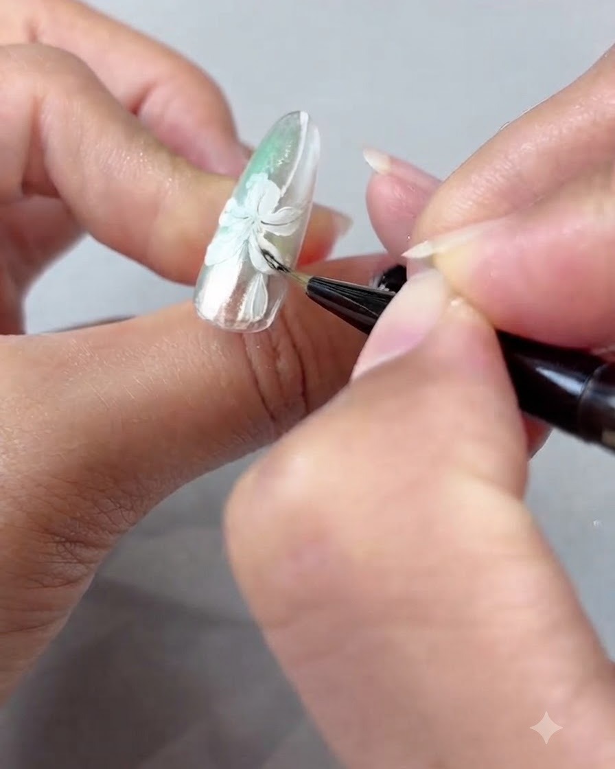 A nail brush delicately blending amber gel shading over white painted lily petals.