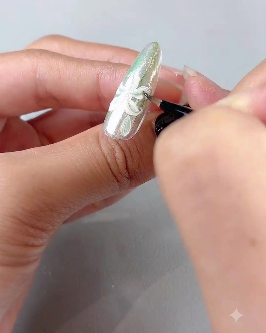 A fine brush painting delicate green leaves around the white lily nail art design.