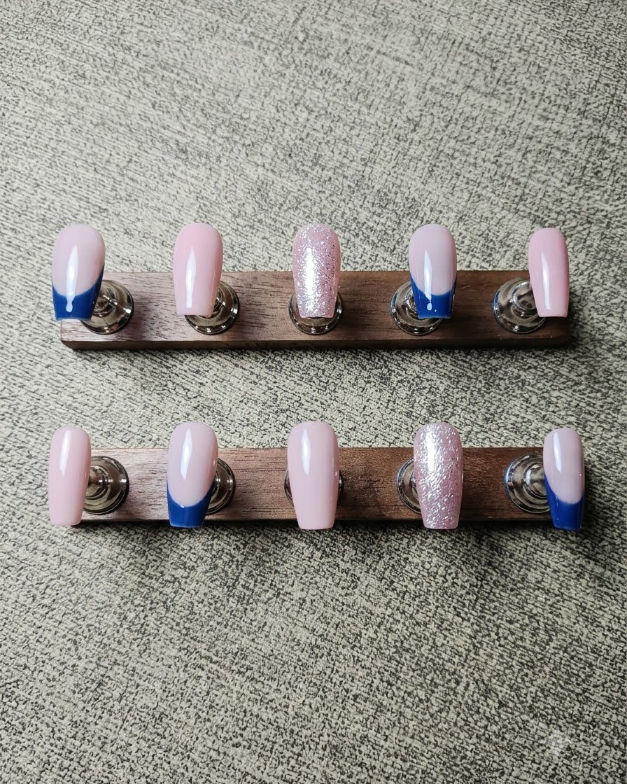 A brush applying silver crushed diamond gel along the smile line of a French tip nail.