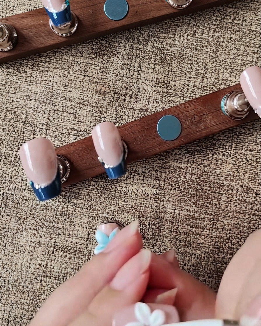 A silicone tool shaping a white 3D gel flower petal on a press-on nail.