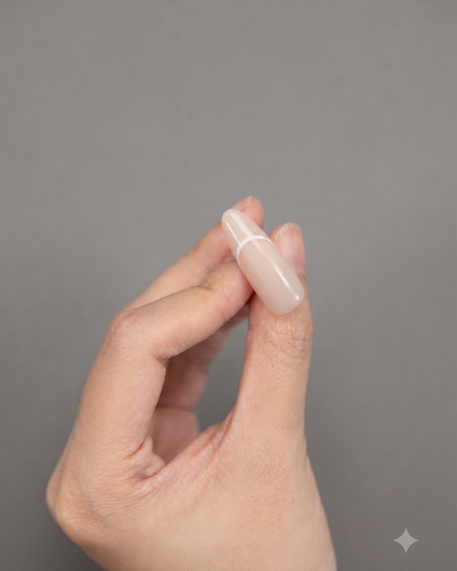 Fingers holding an almond-shaped nail showcasing a completed solid white French tip design.