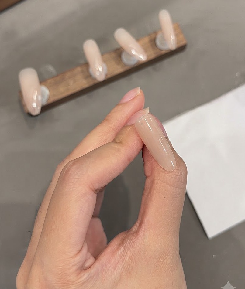 A close-up view of an almond nail showing precise white fine lines painted near the cuticle area.