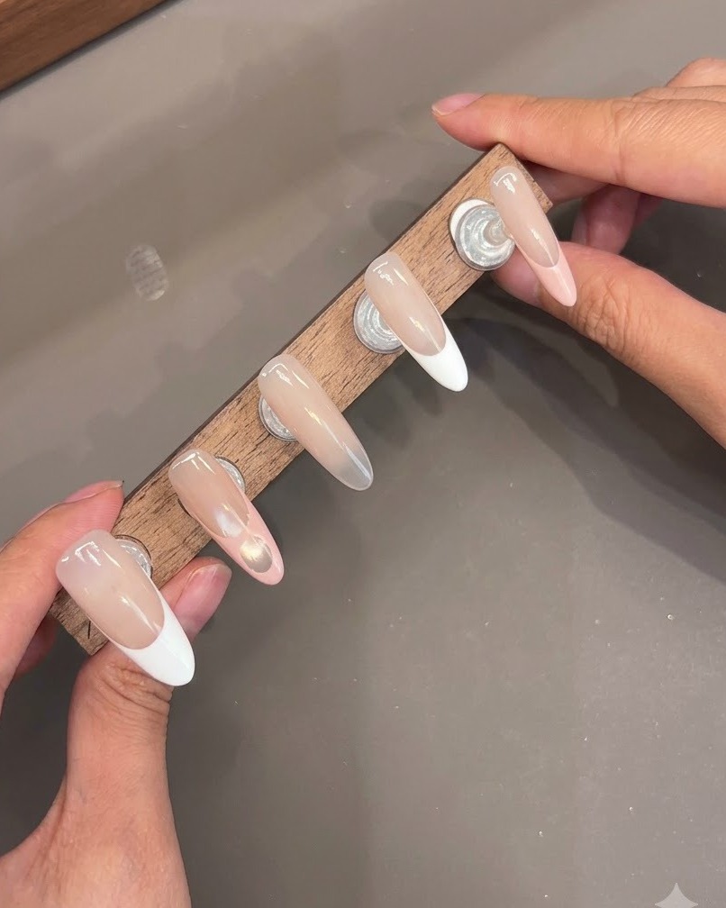 Multiple press-on nails mounted on a wooden stand displaying glossy top coat layers.