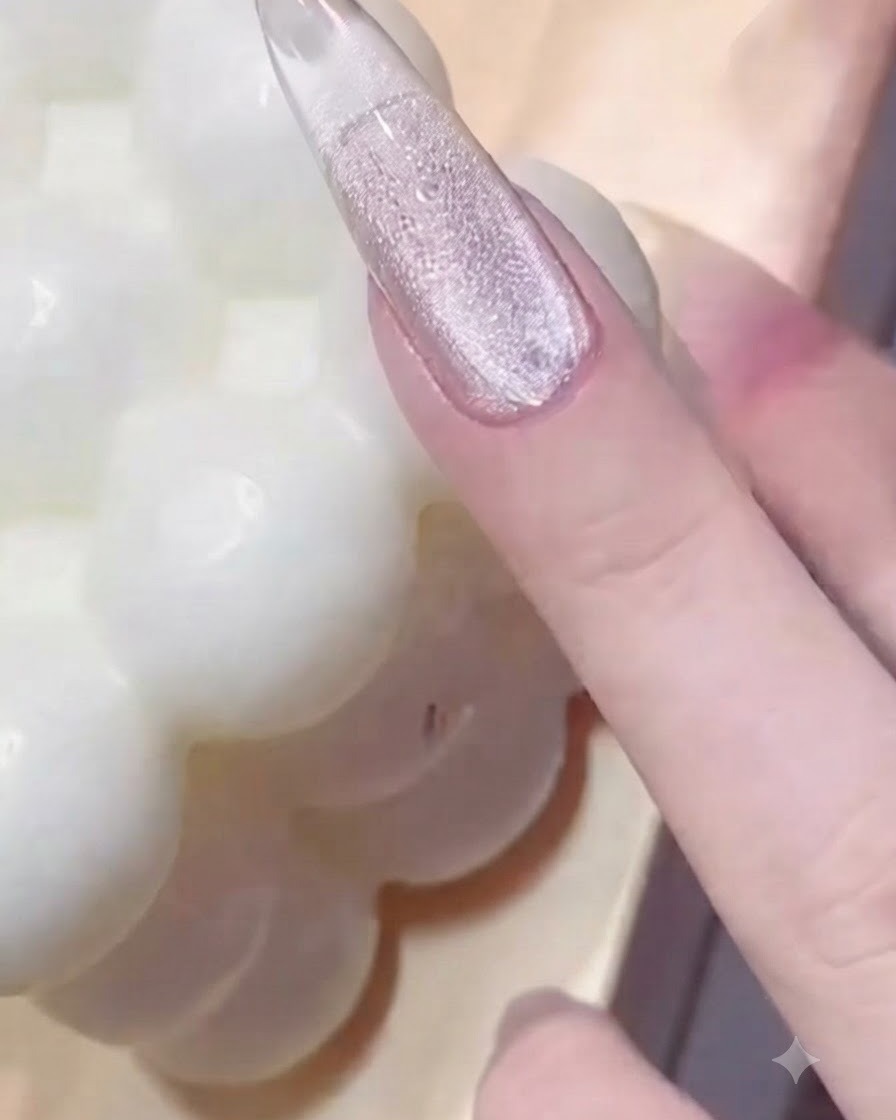 A hand pressing a metal bead ring tool onto a glossy gel-coated fingernail to create textured impressions.