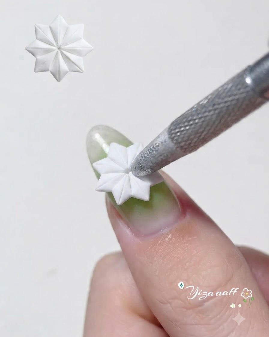 A tool blending translucent green gel evenly over a silver cat eye nail base.