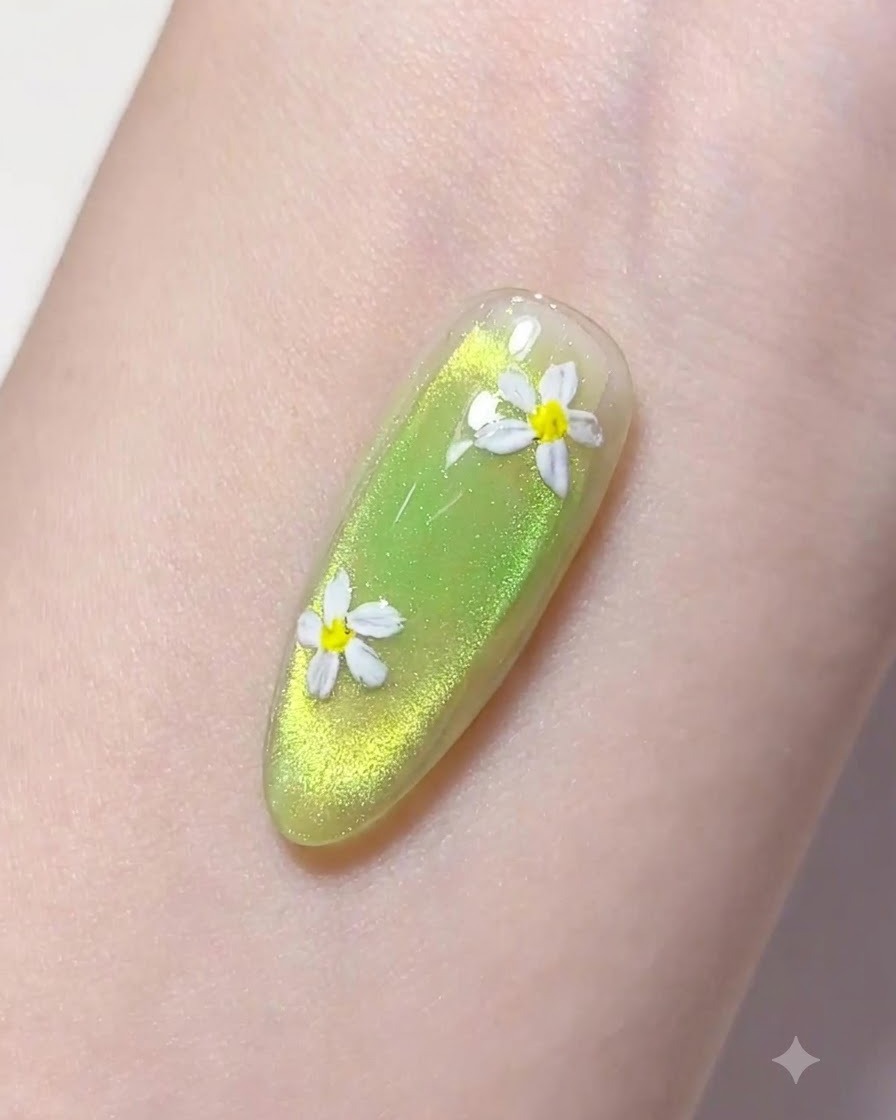 A fine liner brush picking up a drop of clear builder gel above a green manicured nail.