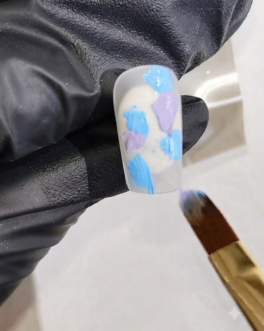 A fine art brush adding vivid pink gel polish streaks into the wet gel mixture on a nail.