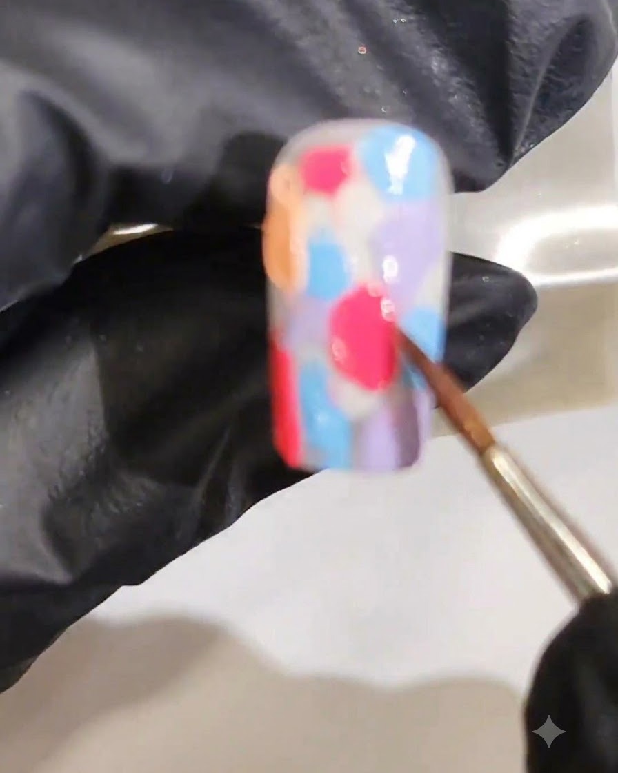 A fine brush blending multiple wet gel colors together to form a smooth marbled watercolor gradient.