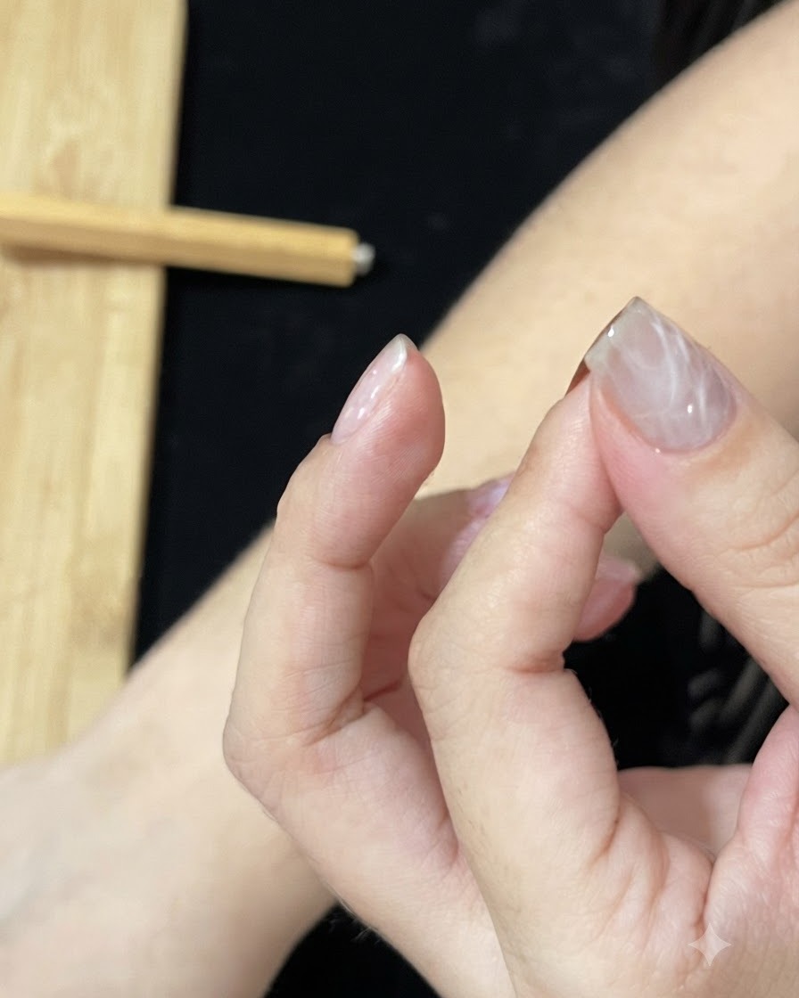 A hand positioned under a UV or LED nail lamp to cure the textured gel layer.