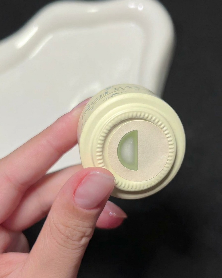 A hand holding a bottle of INCH EASY green gel polish, showing the color indicator label on the top.