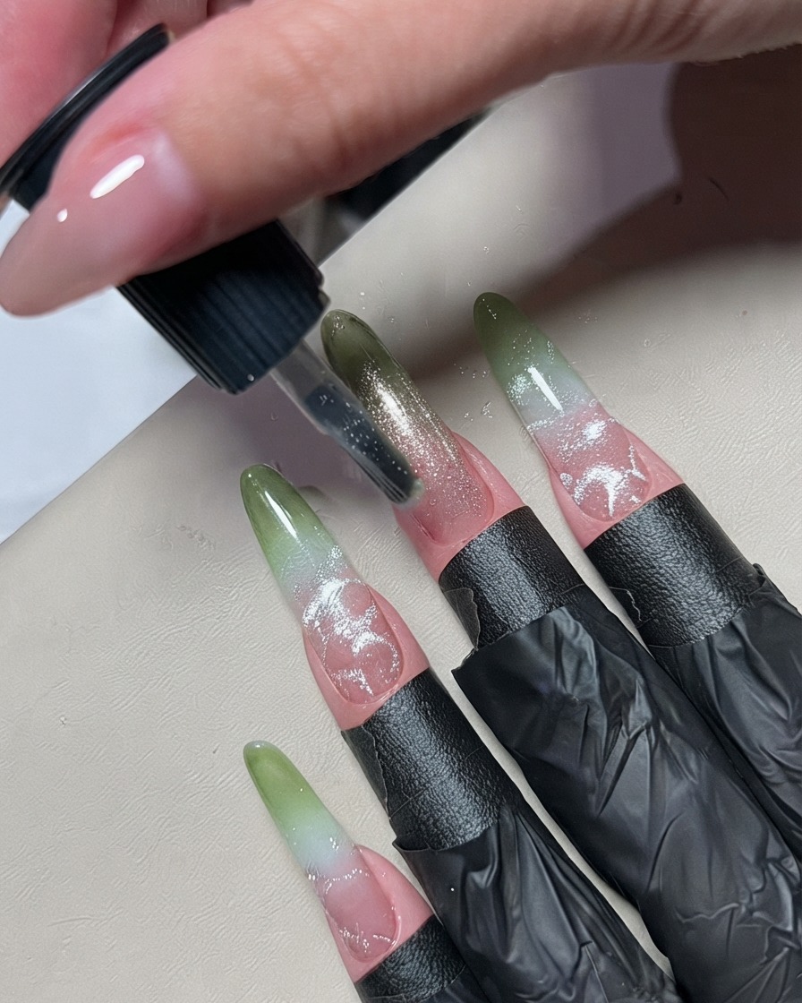 A small nail art brush applying a thin line of silver metallic gel polish down the center of an ombré nail.