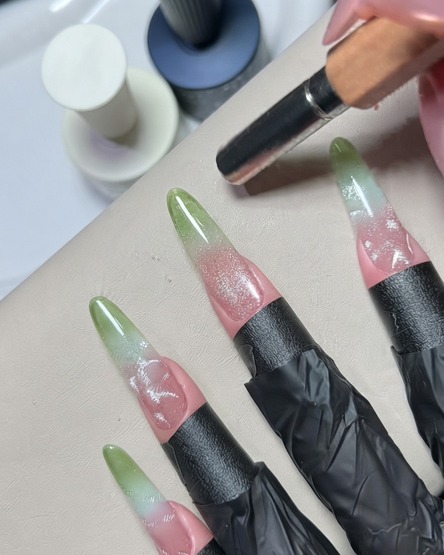 A metal dotting or detailing tool feathering silver gel details on a decorated nail.