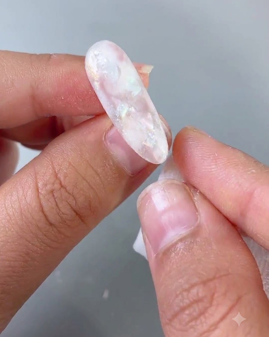 A nail brush applying a smooth coat of top coat onto a finished nail design.
