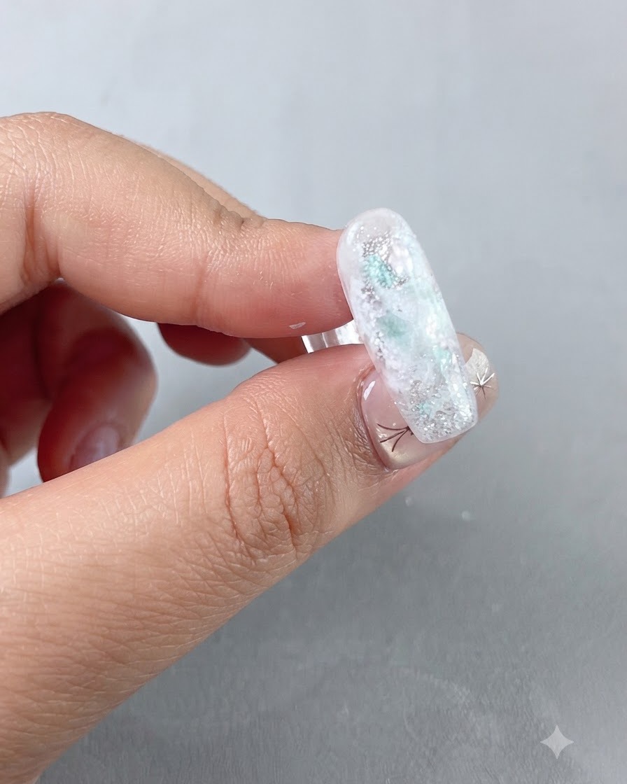 A finished nail design sitting under a UV nail lamp during the curing process.