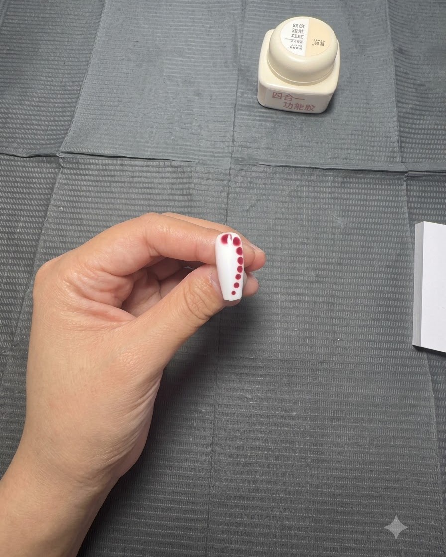 A nail with a line of decreasing red dots sitting undisturbed as the color begins to slightly spread into the wet gel base.