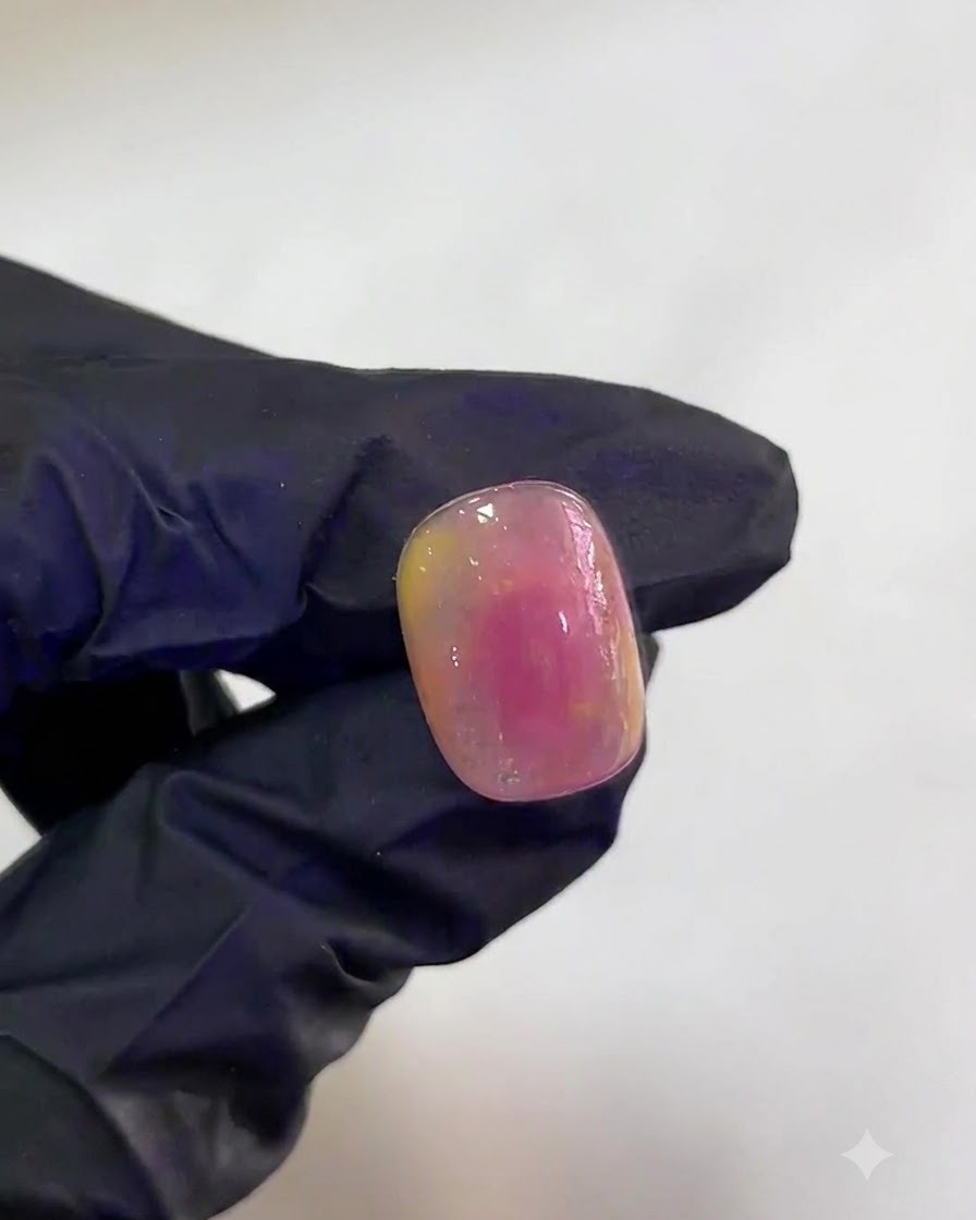 A hand inside a UV/LED lamp curing a pink and yellow watercolor gradient nail.
