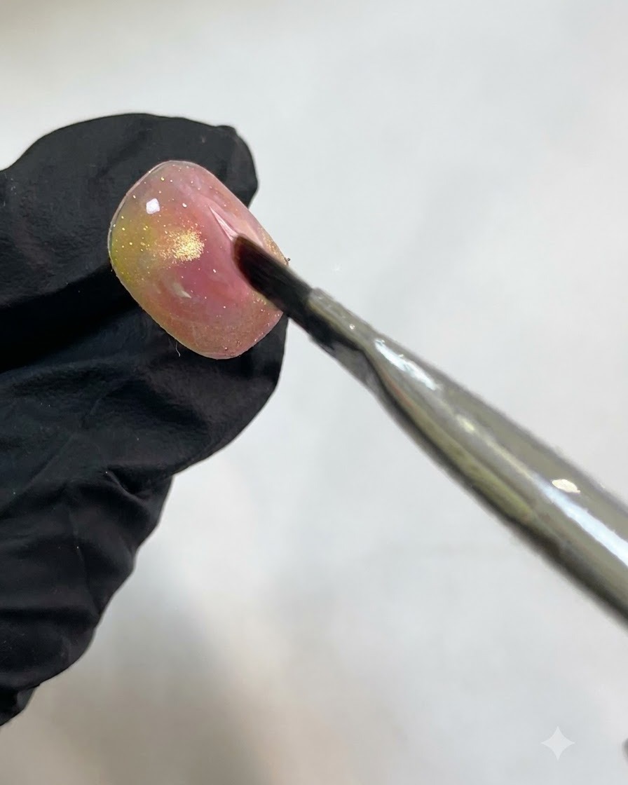 A nail placed under a UV/LED curing lamp after applying translucent white watercolor accents.