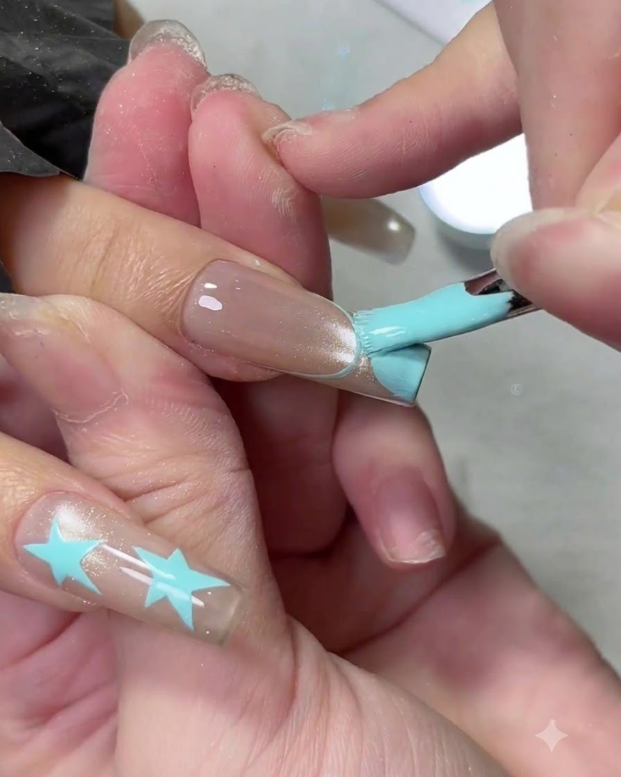 A flat gel brush filling in a light blue French manicure tip on a long nail.