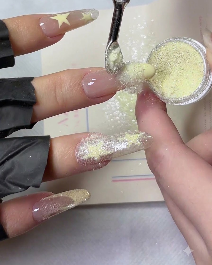 A close-up shot of yellow crushed diamond powder being sprinkled evenly across a wet yellow French manicure tip.
