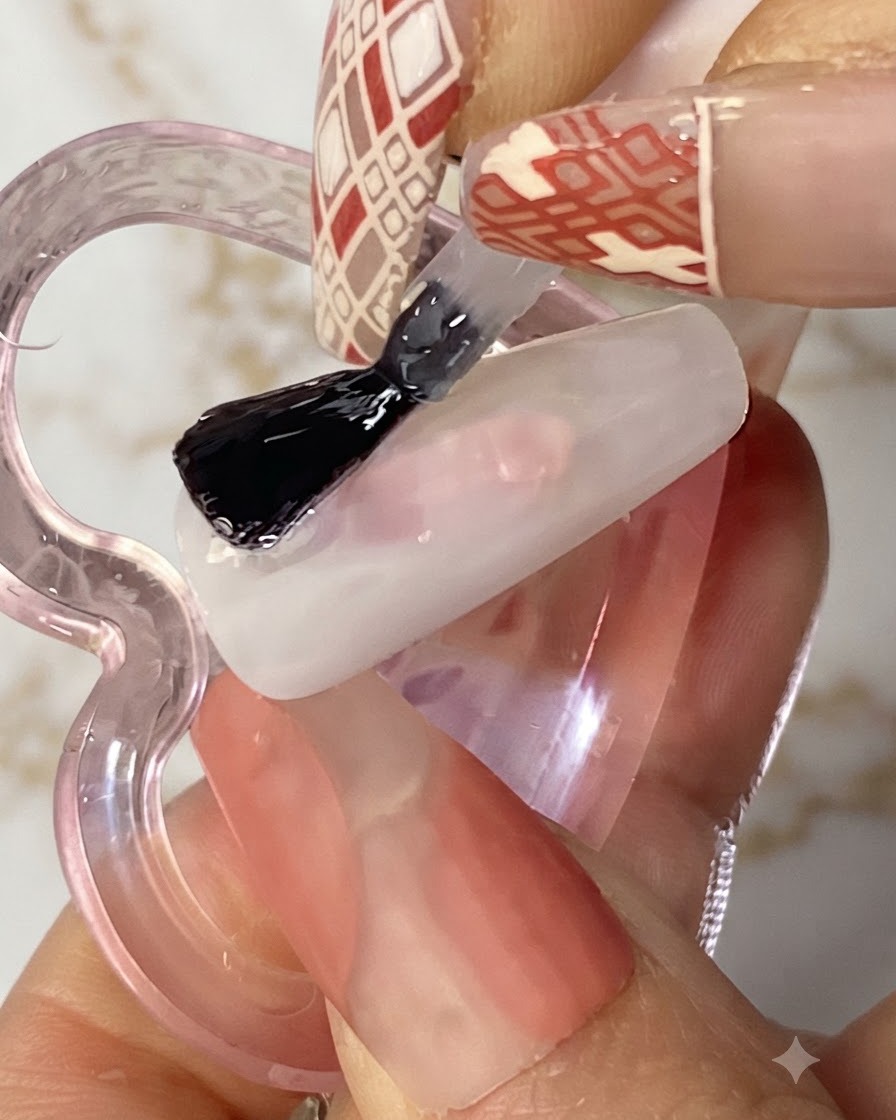A flat gel brush applying a clear layer of solid glue onto a white manicured nail.