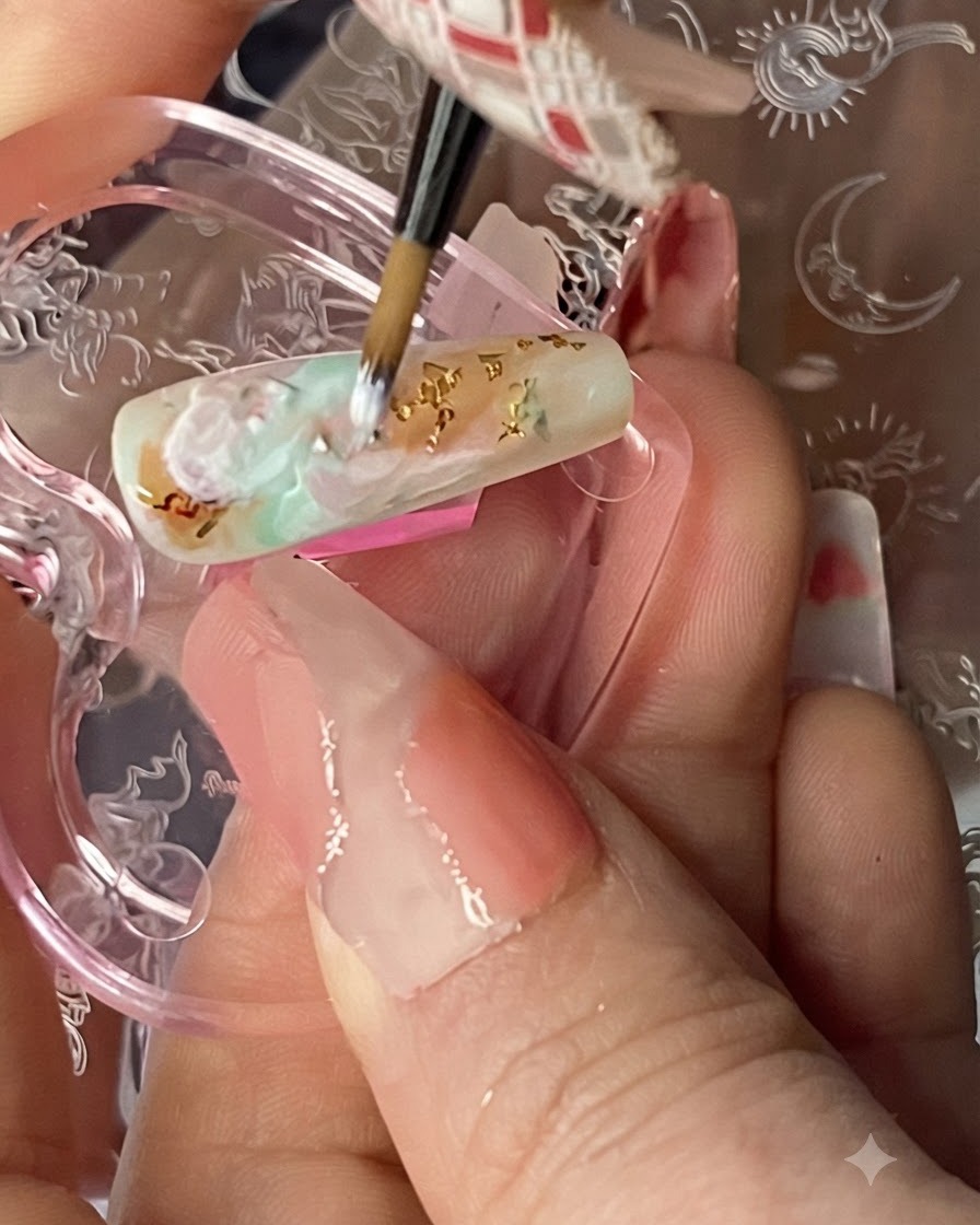 A fine nail art brush drawing delicate, semi-transparent white cloud lines over a multicolored smudged background on a nail.