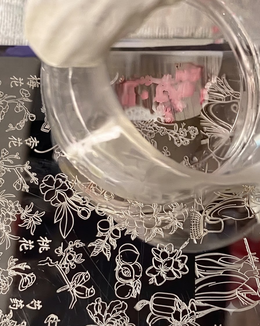 A clear silicone stamper hovering over a stamping plate, capturing the floral nail art design.