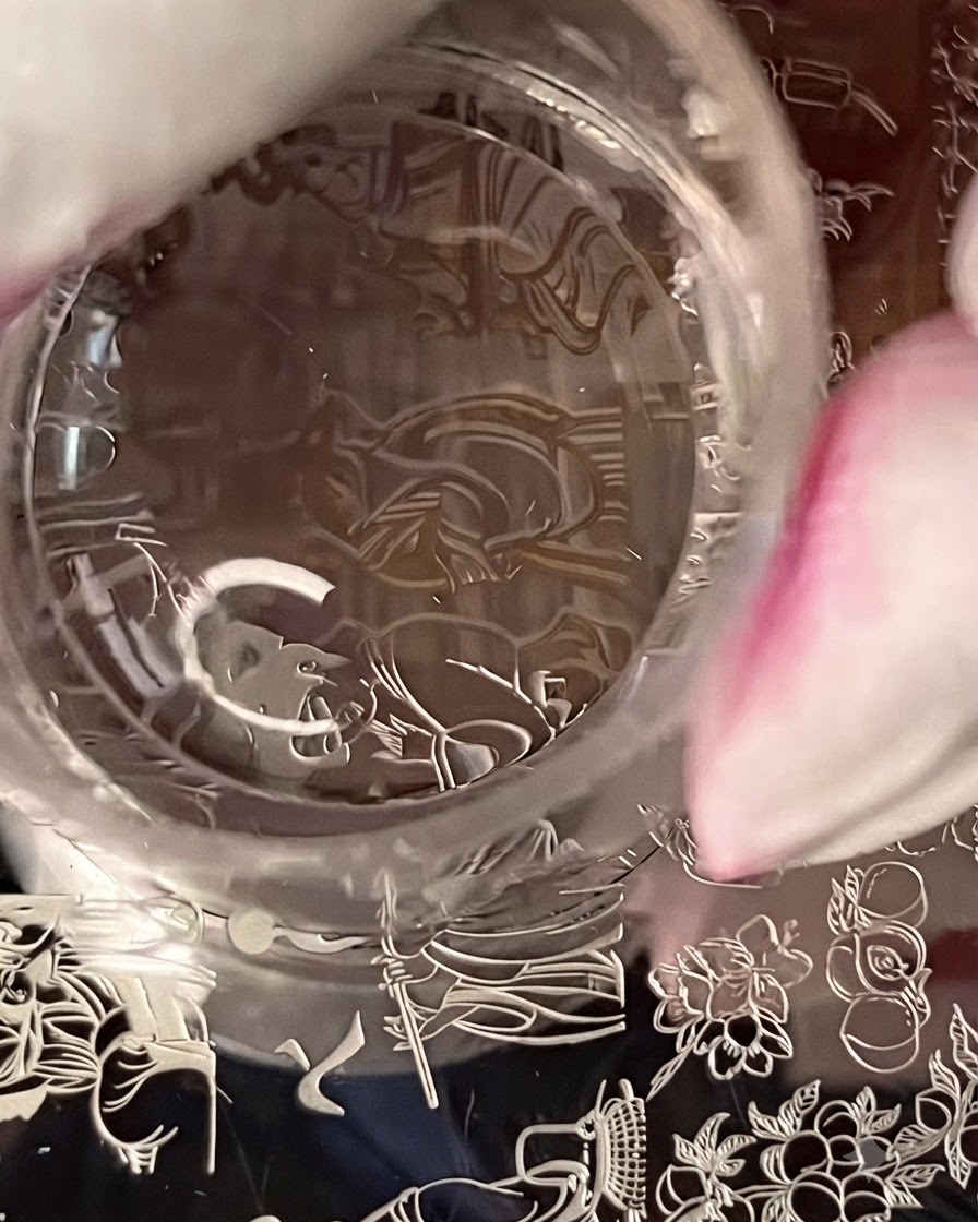 A clear stamper picking up a detailed figure design from a metal stamping plate.