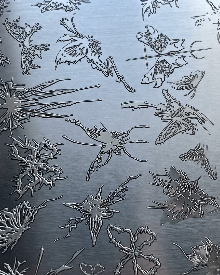 A metal stamping plate featuring various intricate butterfly and abstract patterns.