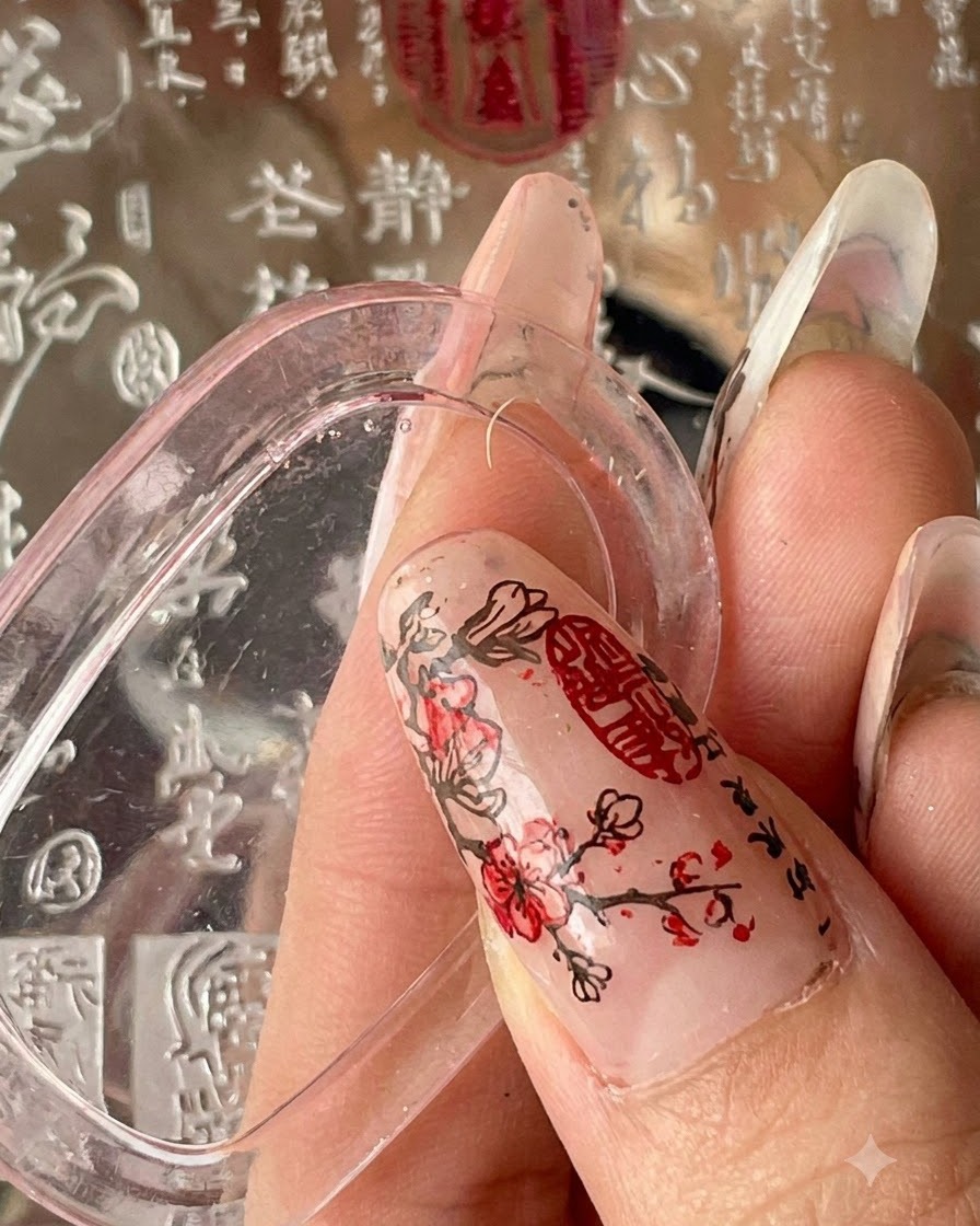 A hand holding a stamper over a textured background plate with script patterns.