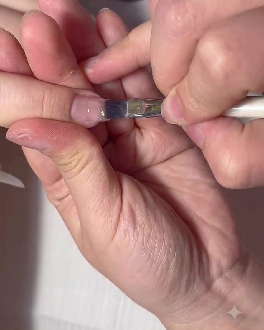 A flat gel brush handling a large bead of clear builder gel on the nail surface.