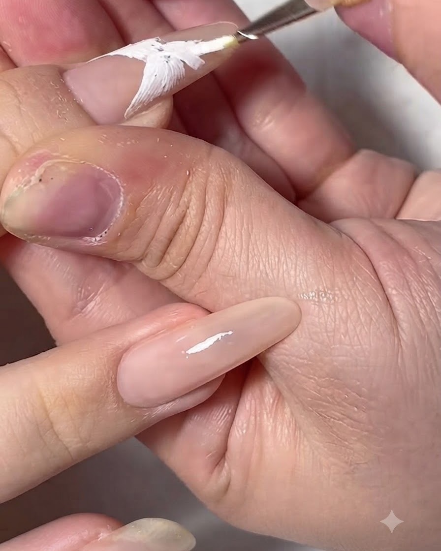 A detailed view of a completed white gel butterfly wing outline on a nail extension.