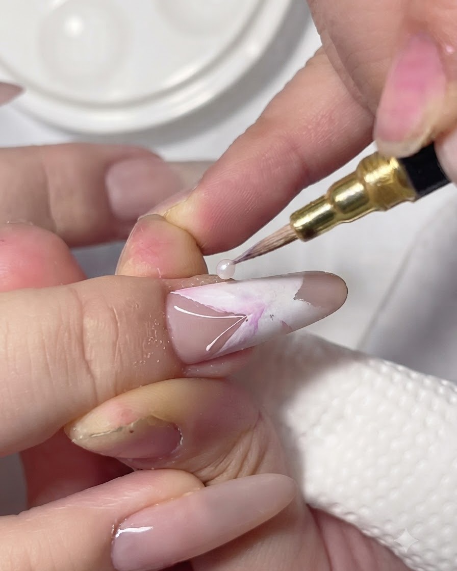 A detailing brush dropping pink and purple pigment into the wet white sections of a nail butterfly art.