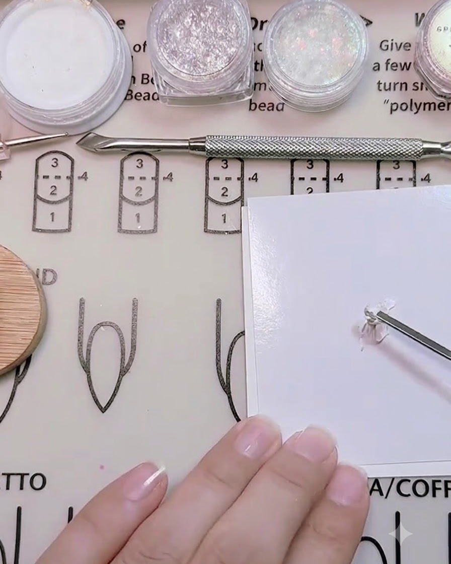 A metal tool mixing white, skin tone, and rose red gel on a palette.
