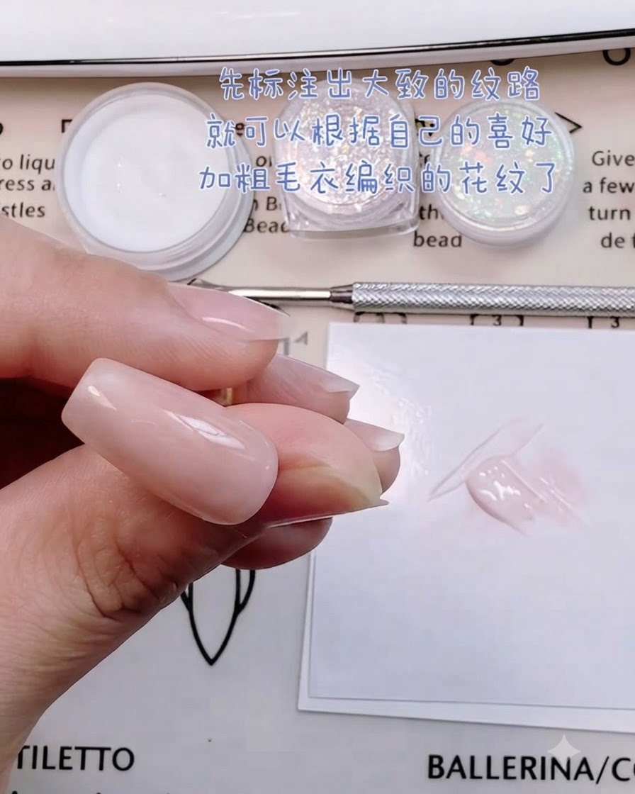 A close-up of a hand holding a fine brush and mixing pink gel next to the nail palette.