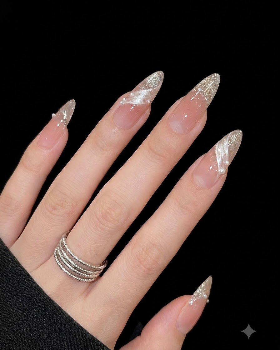 A close-up view of a thumb nail featuring a dimensional white aura swirl and fine silver glitter tips.