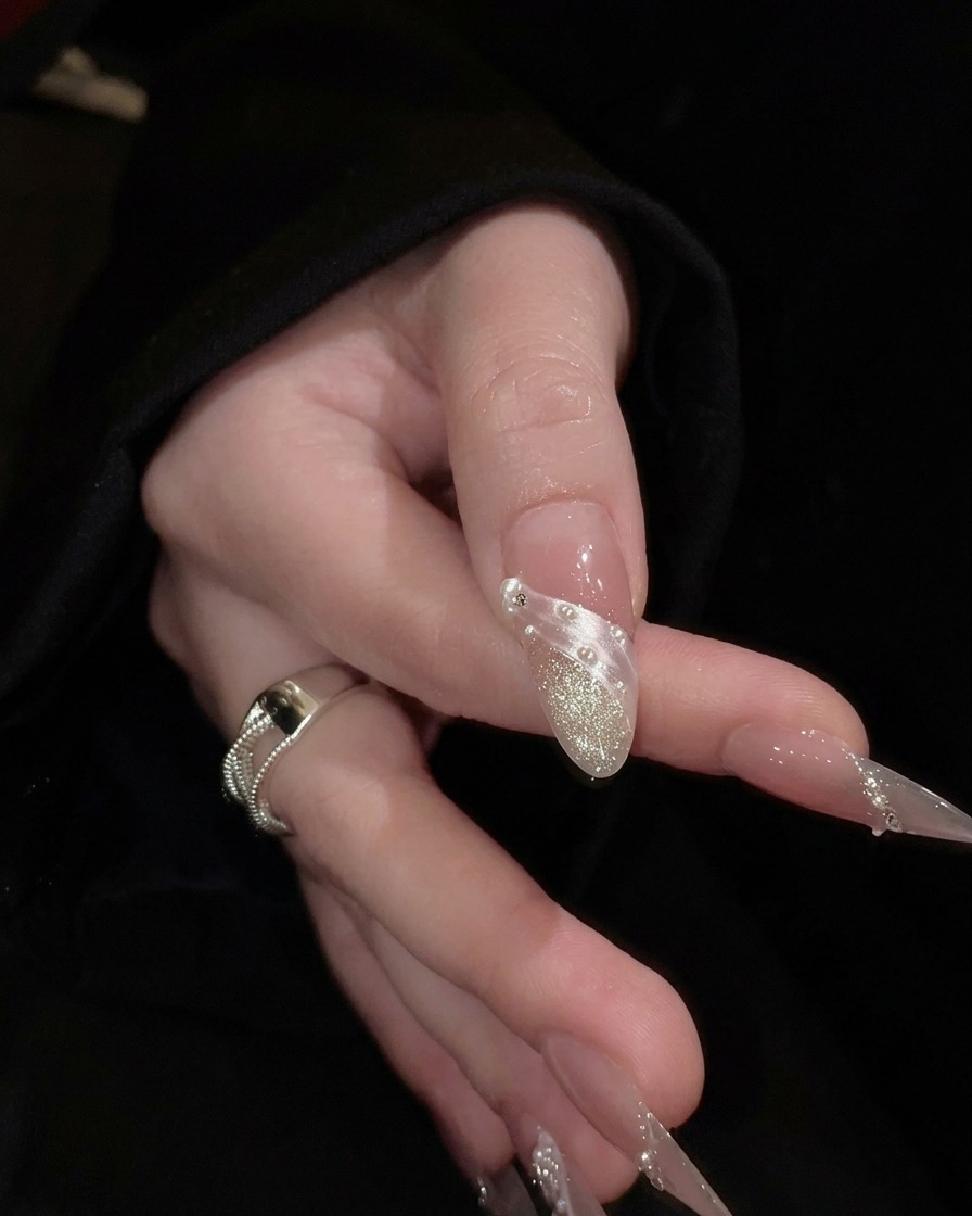A hand posed to showcase the structural apex and length of translucent nude nail extensions.